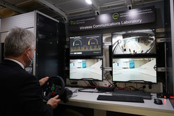 Minister Pinkwart teleoperating vehicles over 5G in front of 4 displays in a van